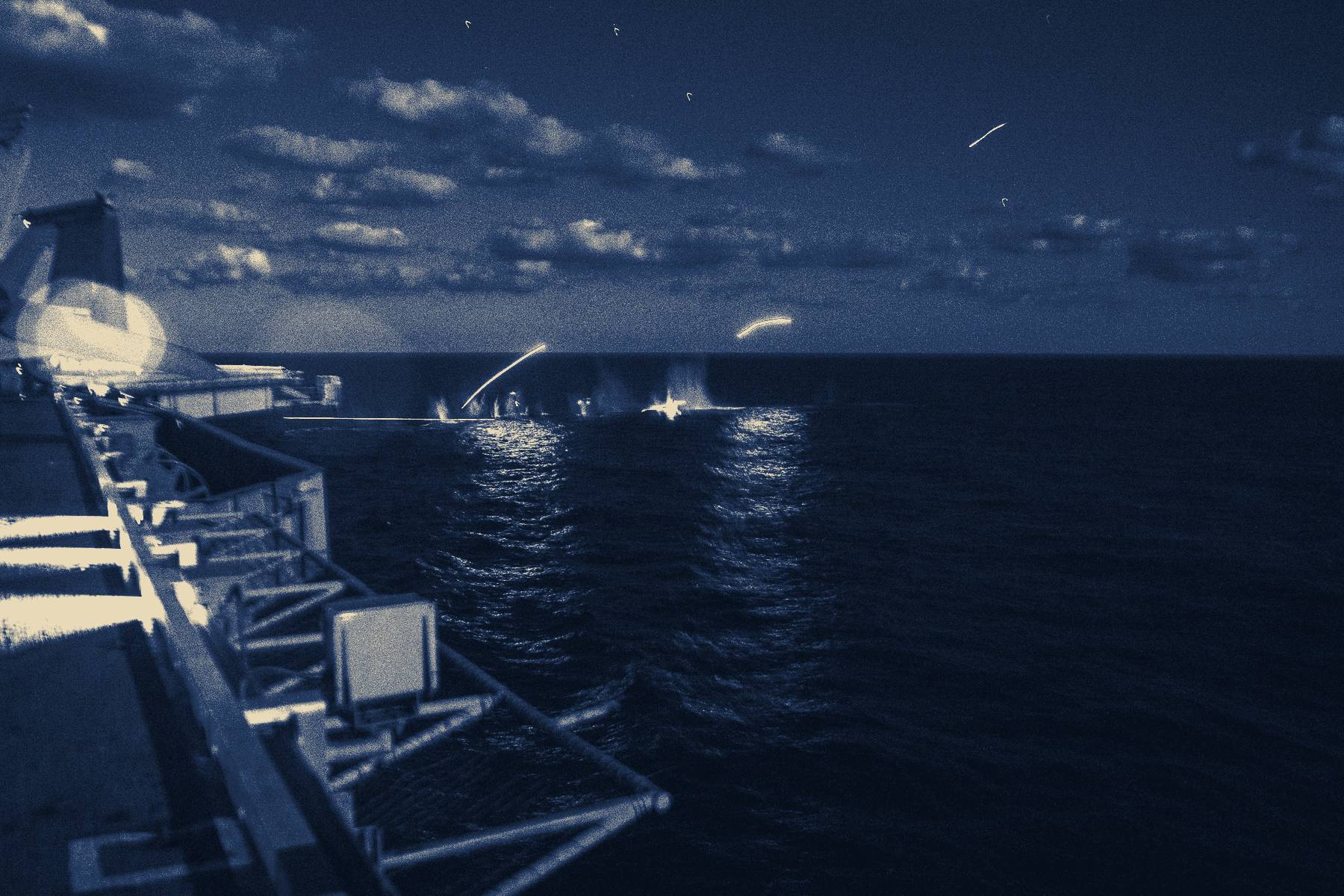 Flares over the sea from a carrier's flight deck at night