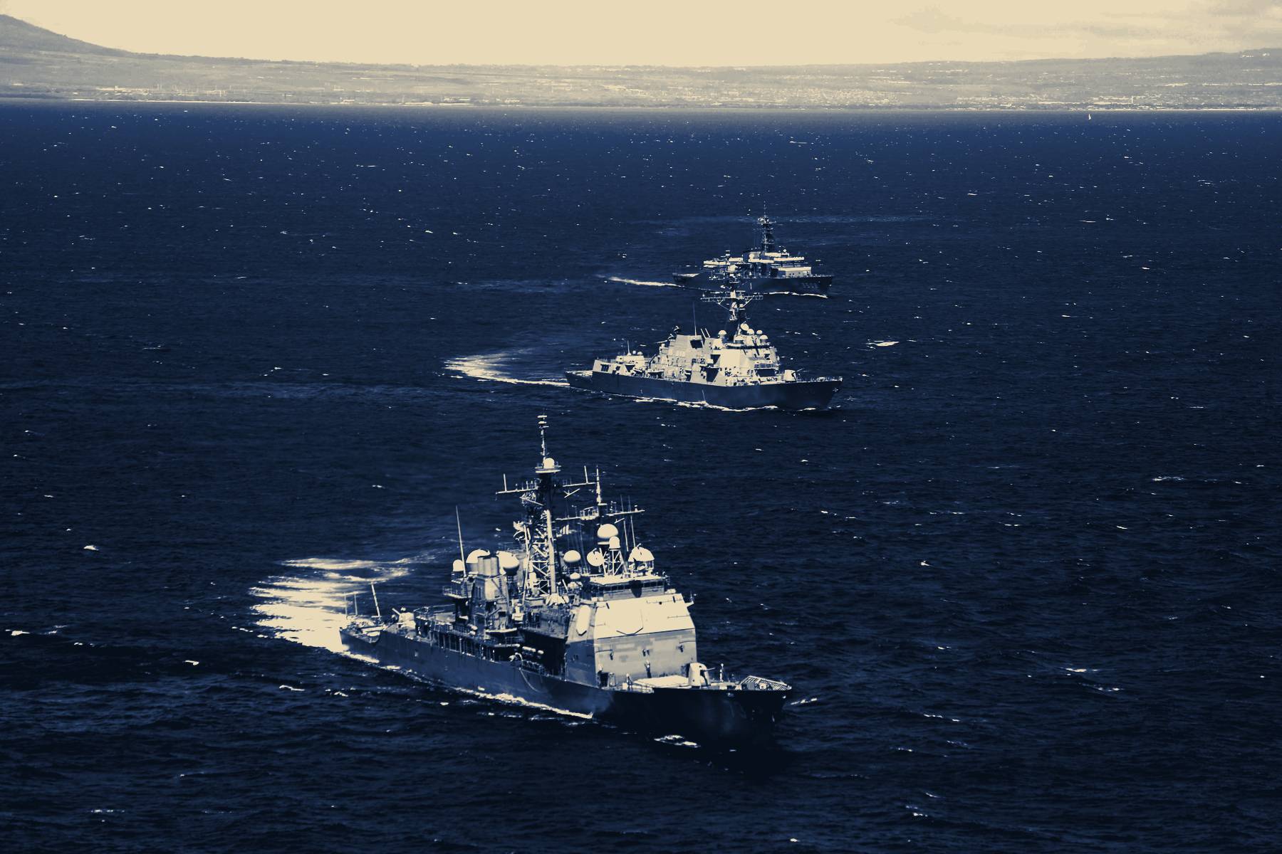 A guided-missile cruiser underway, two destroyers astern